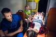 © Anna Kosolapova - A paramedic and a sad little girl sitting beside a young woman lying on a stretcher in an ambulance.