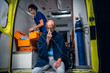 © Anna Kosolapova - Man rescued from the fire sitting in an ambulance car, breathing through an oxygen mask, a female paramedic in the background.