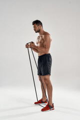 Poster - Young muscular bodybuilder exercising with elastic rubber