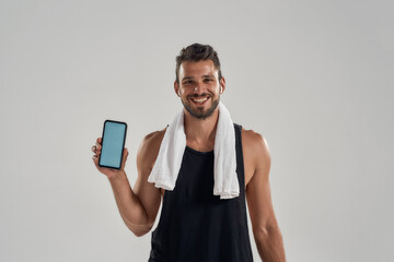 Poster - Happy young muscular caucasian man showing smartphone