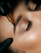 Woman in gloves applying brow tattoo