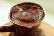 Natural coffee with thick foam, brewed in a copper cezve in the classical way, on a wooden background, macro photo.
