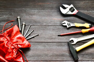 Christmas construction tools. Wrenches, hammer, screwdriver in Santa Claus bag on a wooden background. Set of building tools. Copy space, flat lay. Christmas and New Year card. Advertising.