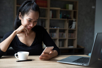 Wall Mural - Remote working at Home office Concept. Businesswoman working online via smartphone. Asian young entrepreneur watching webinars and talking during meeting video conferences calls with team