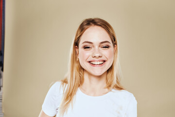 Cheerful blonde gesturing with her hands studio beige background 