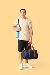 Sticker - Sporty young man with bag and yoga mat on color background