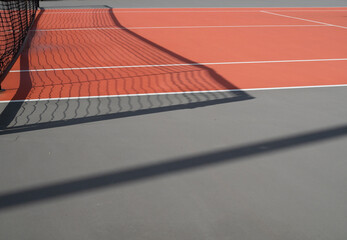 Wall Mural - Black tennis net make shadow on red tennis court. Concept of sport and activity