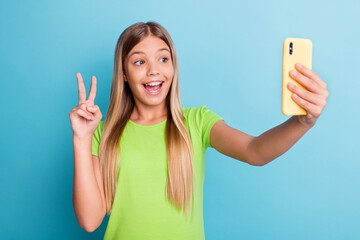 Sticker - Photo of young pretty lovely charming positive smiling girl taking selfie on phone show v-sign isolated on blue color background