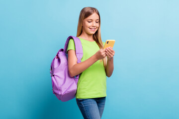 Sticker - Photo of young smiling cheerful good mood positive girl browsing in internet wear violet rucksack isolated on blue color background