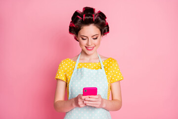 Poster - Portrait of attractive cheerful focused maid housekeeper using gadget browsing news media isolated on pink pastel color background