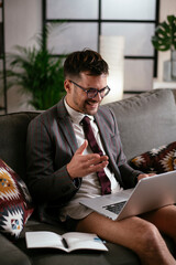 Wall Mural - Businessman with no pants working at home. Young man using the laptop having video call.