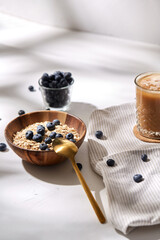 Poster - food, drinks and breakfast concept - oatmeal in wooden bowl with blueberries and spoon, glass of ice coffee on cork drink coaster and kitchen towel