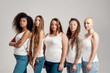 © Svitlana - Group of five beautiful diverse young women wearing white shirt and denim jeans looking at camera while posing together isolated over grey background