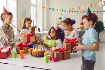 Group of children give presents to their afro friend, who is celebrating a birthday with friends.