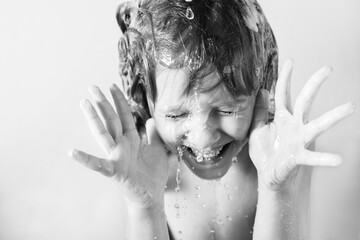 Wall Mural - charming little blonde girl washes her hair in the bathroom with foam on her head. water pours, drop