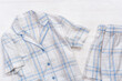 White cotton pajamas with blue checks or stripes, on a white wooden background.  Nightwear for sleeping. Top view.
