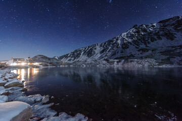Wall Mural - Starry sky in winter Polish Tatras near a mountain lake covered with ice