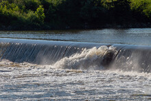 A Small Breach In The Dam At A Kansas River Allows Water To Gush Through And Make Splashes. Bokeh.