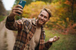 Joyful unshaven man taking selfie on mobile phone while strolling