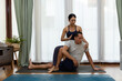 © JR-50 - teaching practice, .Private yoga teacher with the student workout at home. Asian couple in sports clothes on the mat while doing yoga at home