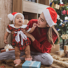 Wall Mural - merry christmas and happy Holidays. mother held her daughter near the christmas tree and decorate the christmas tree indoors. the morning before Xmas. Portrait loving family close up.