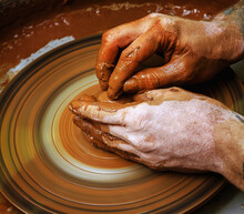 The Potter's Hands Are Gently And Surely Formed By A Clay Pot On A Potter's Wheel.