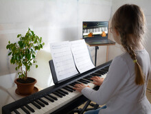Girl Learning To Play The Piano In Distance Learning Via Laptop Over The Internet