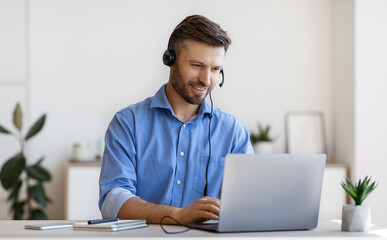 handsome young man in headset study online, watching webinar on laptop