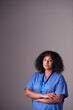 © Monkey Business - Studio Portrait Of Female Nurse Wearing Scrubs Standing Against Grey Background