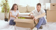 © lenetsnikolai - Portrait of happy couple looking at laptop computer together sitting in new house, surrounded with boxes