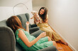© Olga - Two pregnant women sitting in armchairs at home playing with miniature poodle dog