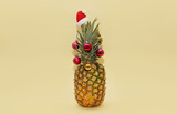 Fototapeta Psy - Ripe beautiful pineapple decorated with Christmas balls and Santa hat on a light yellow background. Creative idea of a Christmas tree for vegetarians.