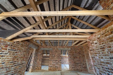 Wall Mural - Attic of a building under construction with wooden beams of a roof structure and brick walls.