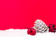 Red kokina flower, white pine cone and bright red new year ornament on red background and snowy backdrop for Christmas
