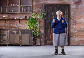 Wall Mural - Cheerful senior woman holding kitchen knives indoors. Security and self-defense concept.