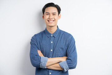 Photo of an Asian man standing with his arms crossed and smiling on a white background