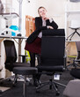 Portrait of young attractive saleswoman standing in interior of chair store
