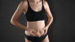 © Tatsiana - The young woman shows changes in her figure. Concept of body care, proper nutrition, excess weight, women's health. Woman in underwear on grey background.