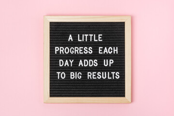 Wall Mural - A little progress each day adds up to big results. Motivational quote on black letter board on pink background. Concept inspirational quote of the day. Greeting card, postcard.