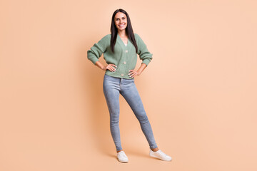 Poster - Full length photo of positive happy woman hold hands waist wear green cardigan jeans isolated on beige color background