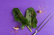 © Foodlovers - Fresh spinach, spices and a meat fork on a violet surface