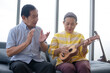 asian grandma grandpa playing ukulele with smile in living room