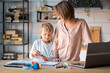 © yavdat - Young mother with toddler child working on the computer from home. multi tasking, freelance and motherhood concept working at home as her cute little boy plays on a tablet