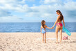 © New Africa - Happy mother and daughter on sandy beach near sea, space for text. Summer holidays with family