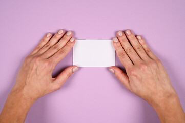 Hand holds white blank sign on purple background