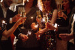 © maxbelchenko - Sparkling sparklers in the hand. Group of happy people holding sparklers at the party. Young friends clinking glasses of champagne  in a nightclub. Celebration, people and holidays concept.