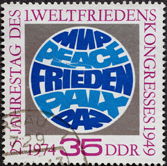 Wall Mural - GERMANY, DDR - CIRCA 1974 : a postage stamp from Germany, GDR showing a globe with the word peace in 5 languages. 25th anniversary of the first World Peace Congress, Paris