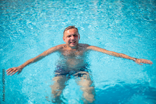 Fotografía handsome guy half-naked cheerful man smiling laughing in blue water swimming pool