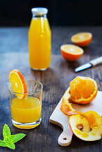 Orange Juice In A Glass And Bottle With Fresh Oranges And Mint Leaves