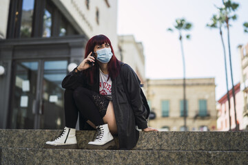 Poster - Selective focus shot of an attractive female wearing a facial mask with a phone in her hands